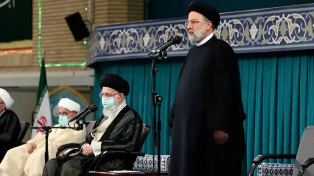 Ibrahim Raisi standing with the leader