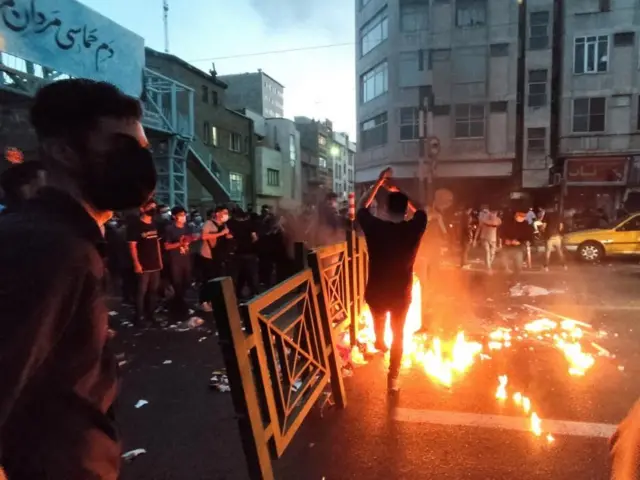 Protesters light a fire during a protest in Tehran on 21 September