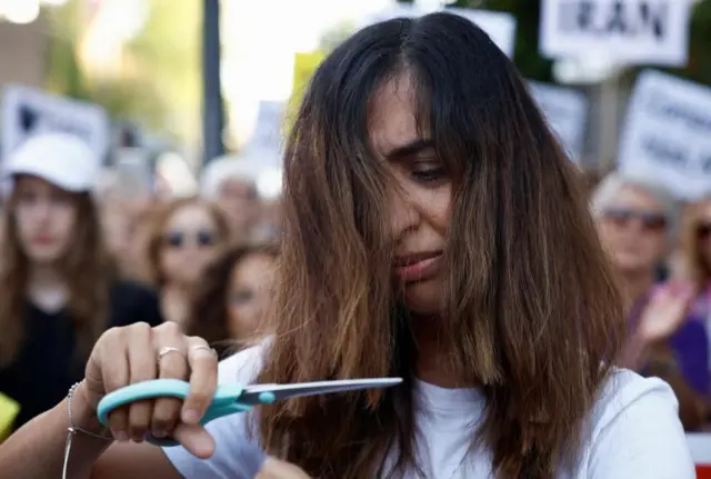 A woman cuts her hair at a protest outside the Iranian Embassy in Madrid, Spain on 6 October