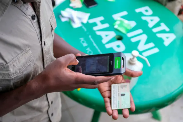 : A customer care specialist helps out with services during the new Sim Card registration outside Safaricom (one of the leading mobile telephone network providers in Kenya) customer care shop.