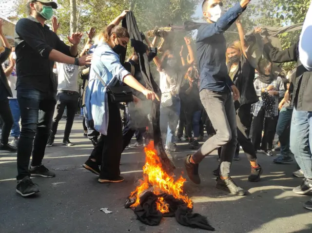 Women set their headscarves on fire on a street in Tehran on 1 October