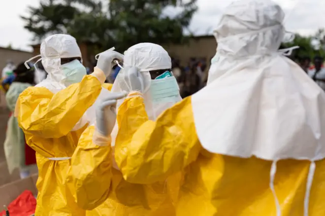 Red Cross workers don PPE prior to burying a 3-year-old boy suspected of dying from Ebola on October 13, 2022 in Mubende