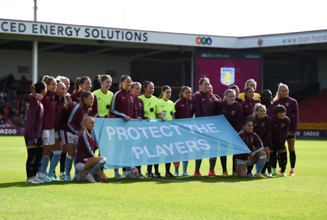 Players hold a 'Protect the Players' banner ahead of Aston Villa vs West Ham