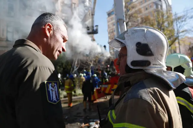 Mayor Vitali Klitschko talking to a firefighter with destruction in the background.