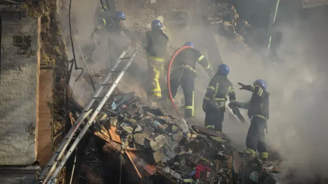 Ukrainian rescuers in Kyiv search through rubble from a residential building destroyed by a Russian drone attack