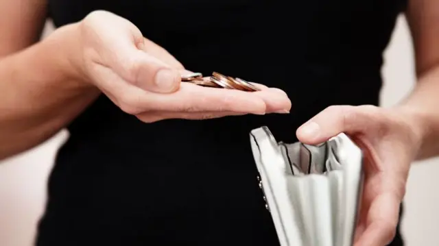 Woman holding coins and white leather purse