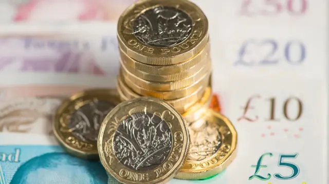 A stack of pound coins on top of pound notes