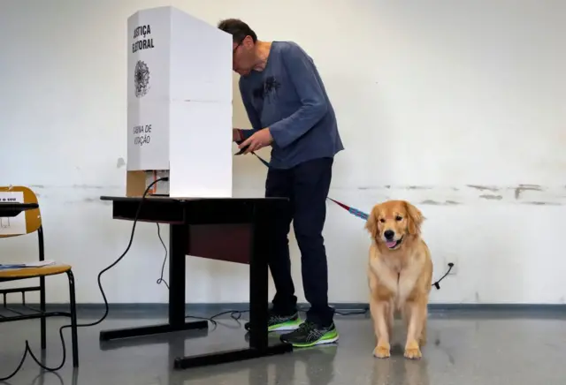 A man votes as his dog sits next to him at a polling station during the legislative and presidential election, in Sao Paulo, Brazil, on October 2, 2022