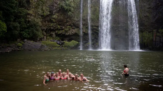 women in pool near waterfall