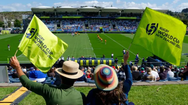 spectators waving flags at rugby match