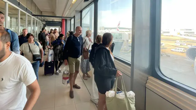 People look out the window to see Boris Johnson leaving a plane at Gatwick