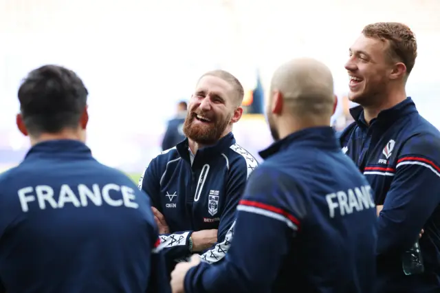 Sam Tomkins of England jokes with members of France's team