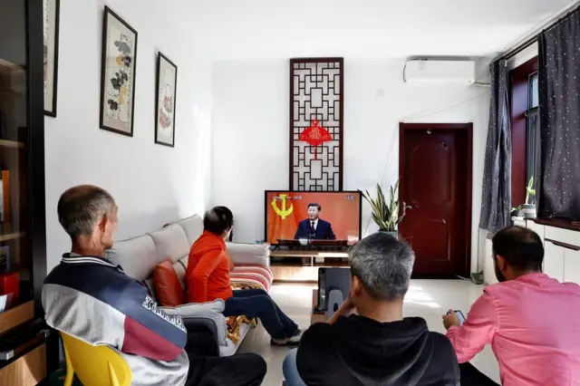 A Chinese family in Beijing watch the proceedings on a TV in their living room