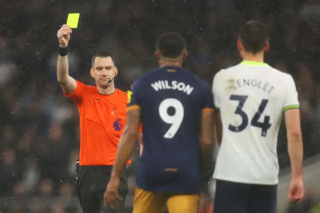 Referee Jarred Gillet shows a yellow card to Callum Wilson