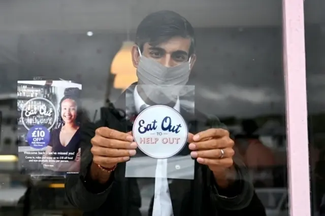 The then-Chancellor Rishi Sunak places an Eat Out to Help Out sticker in the window of a business in Scotland