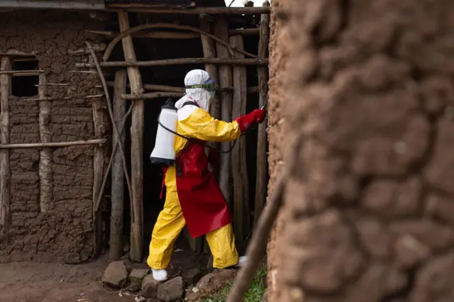 A Red Cross worker sanitizes a house after burying a 3-year-old boy suspected of dying from Ebola on October 13, 2022 in Mubende, Uganda.