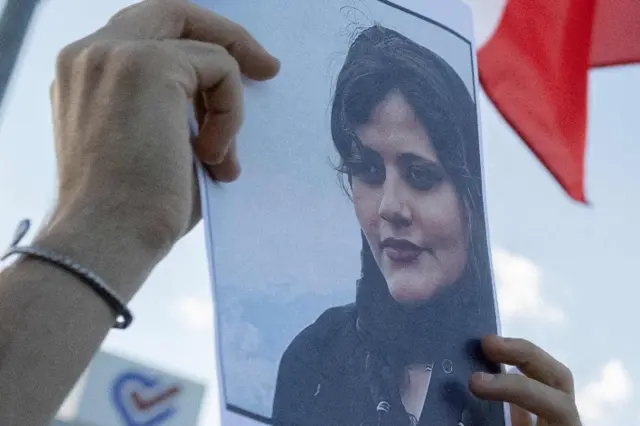 Close-up of a protester holding an image of Mahsa Amini