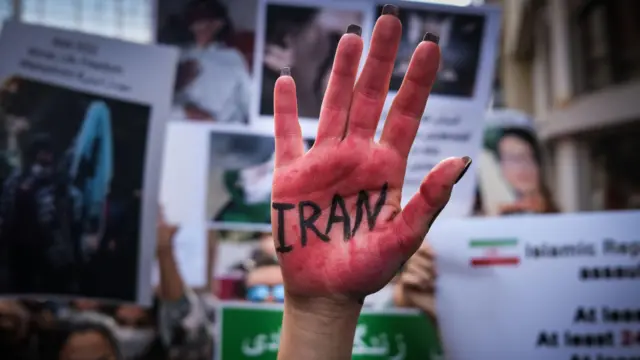 Iranian people hold pictures of Mahsa Amini with their hands painted in red during a protest in Istanbul, Turkey