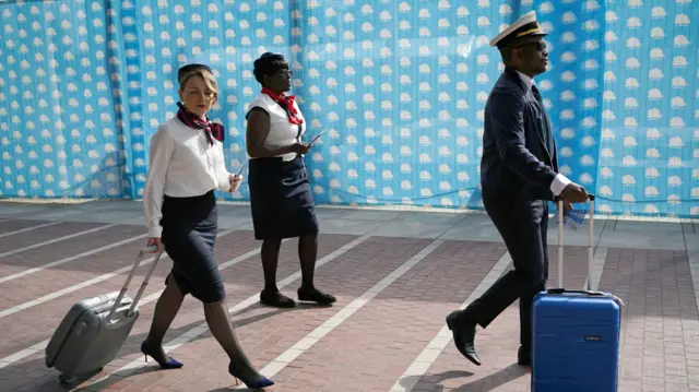 Refugees, dressed as airplane staff, get ready to perform a 'one-way ticket to Rwanda' protest