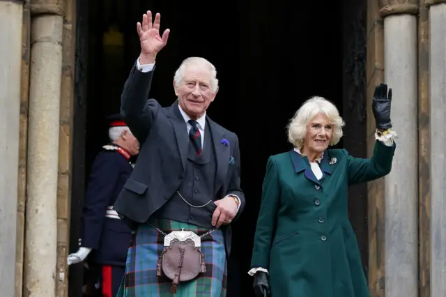 King Charles III and the Queen Consort wave as they leave Dunfermline Abbey