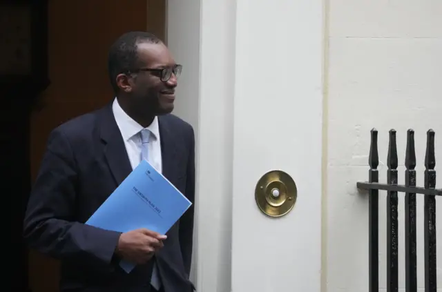 Kwasi Kwarteng carries a copy of the mini-budget