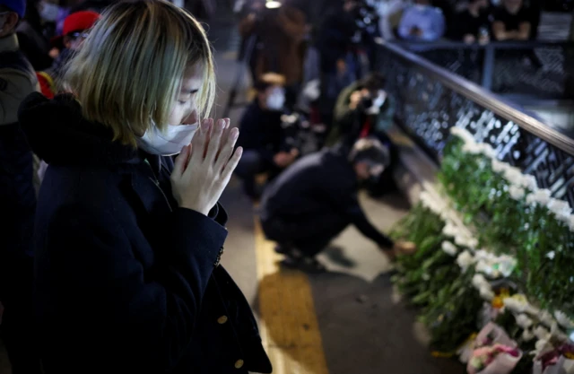 Woman prays near to the scene where a stampede killed dozens in Seoul, South Korea