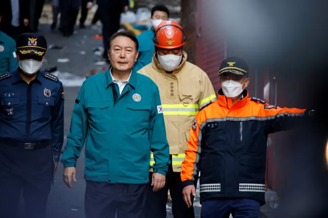 South Korean President Yoon Suk-yeol walks accompanied by emergency services