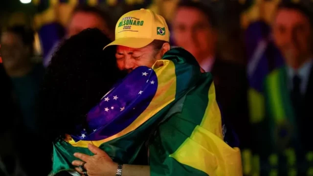 Two people hugging wearing the colours of Brazil's flag