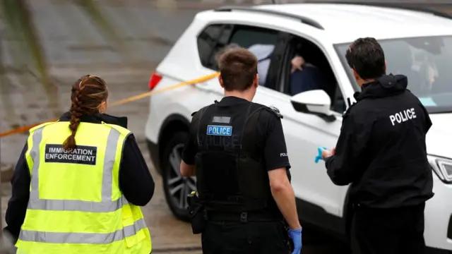 Police officers stand next to a car believed to have been used in the attack