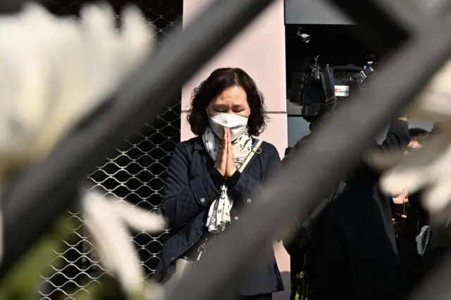 A woman prays in tribute to those who were killed at a makeshift memorial outside the subway station in the district of Itaewon in Seoul on October 31