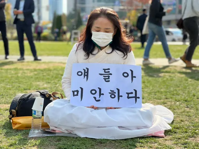 Lee Insook's sign says “I’m so sorry, guys”