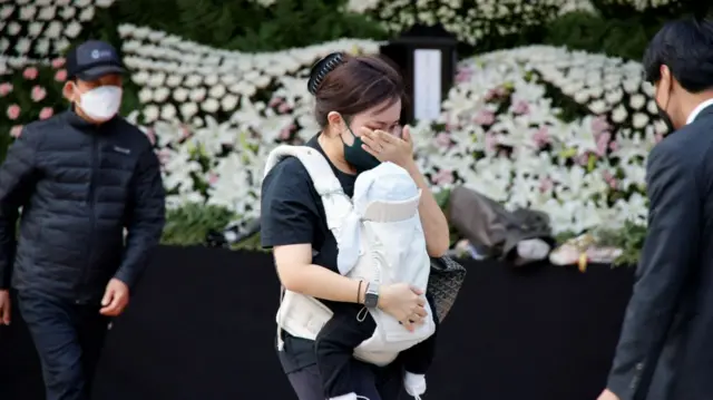 A person mourns at a group memorial for the victims of a stampede during a Halloween festival, at Seoul City Hall Plaza in Seoul, South Korea, October 31, 2022.