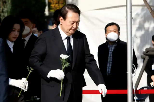 South Korean President Yoon Suk-yeol and his wife Kim Kun-hee hold flowers at a memorial altar