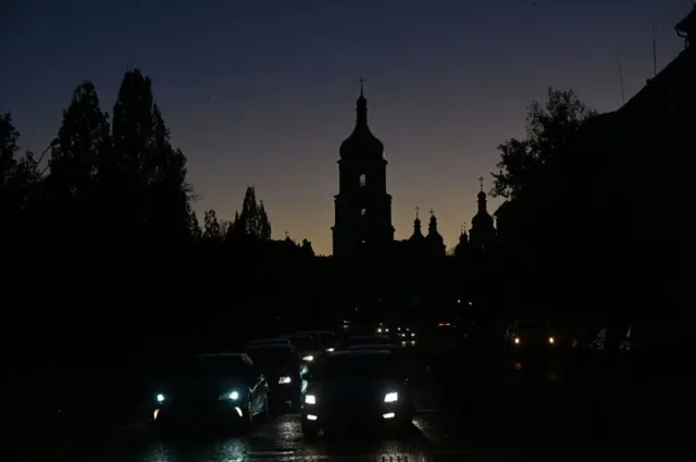 Vehicles drive along a street with Kyiv's Saint Sophia Cathedral silhouetted in the background