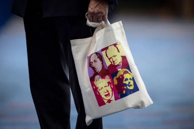 An attendee carries a bag featuring former Conservative Prime Ministers' illustrations at the Conservative Party Conferenc