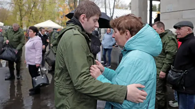 Conscripted men say goodbye to relatives at a military recruiting office in Moscow