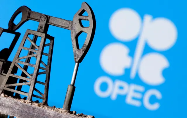 A 3D printed oil pump jack is seen in front of displayed OPEC logo