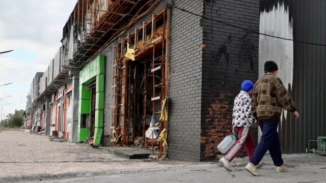 Two people walk through the liberated town of Lyman in Ukraine