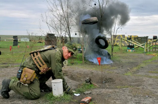 A man crouches to defend himself from an explosion during army training in Rostov-on-Don