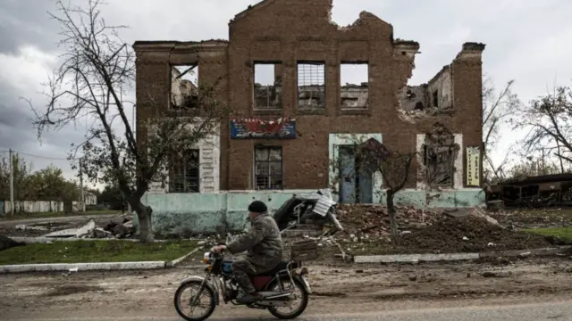 A man rides past a damaged building after Russian forces withdrawn from Drobysheve village, the city of Lyman in the Donetsk region, Ukraine on October 05, 2022