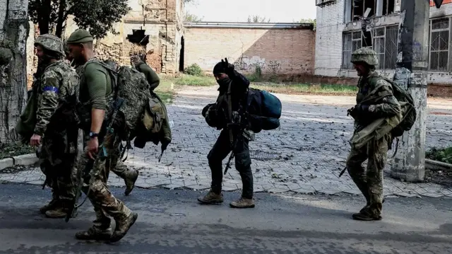 A man flashes a victory sign as he walks through the Donetsk region with Ukrainian soldiers