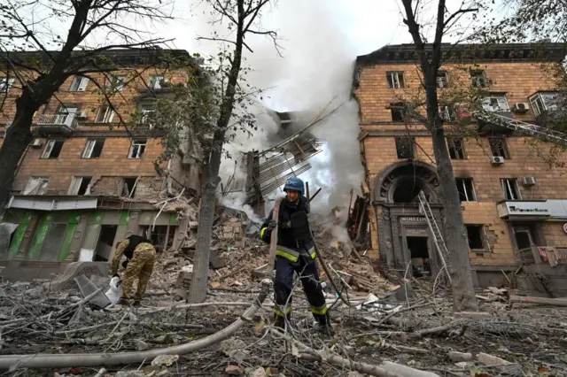 A rescue worker in front of a residential building heavily damaged by air strikes in Zaporizhzhia, Ukraine