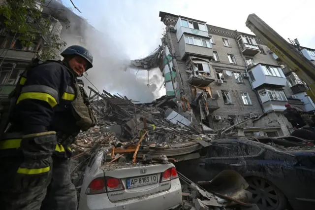 A rescue worker at the scene of a heavily damaged residential building in Zaporizhzhia, Ukraine