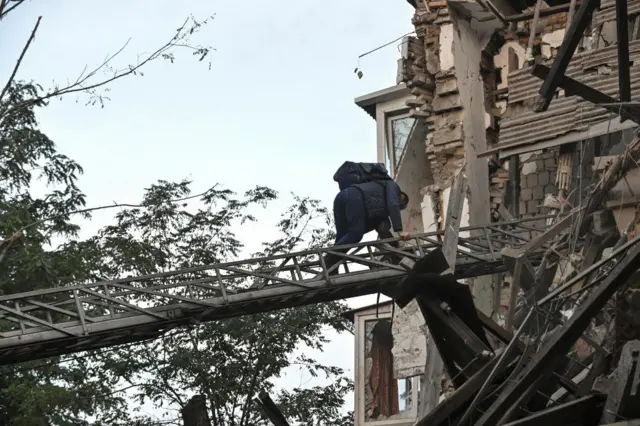 A resident climbs down a rescue ladder from a damaged residential building in Zaporizhzhia, Ukraine