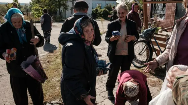 Local residents take some food distributed by a Ukrainian soldier in the recently retaken town of Yampil, near Lyman, in Donetsk region on October 6, 2022, amid the Russian invasion of Ukraine. -