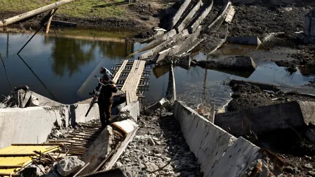 A local resident carries his bicycle as he walks through the ruins of the bridge that was destroyed during the fighting between Russian troops and Ukrainian army, amid Russia's attack on Ukraine, in Bakhmut, Donetsk region, Ukraine October 6, 2022