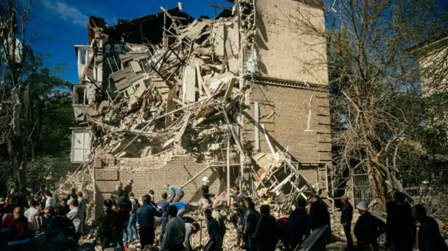 Volunteers remove the rubble of a building as they look for survivors after a strike in Zaporizhzhia on 6 October, 2022