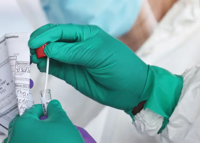 A health care worker seals a coronavirus swab