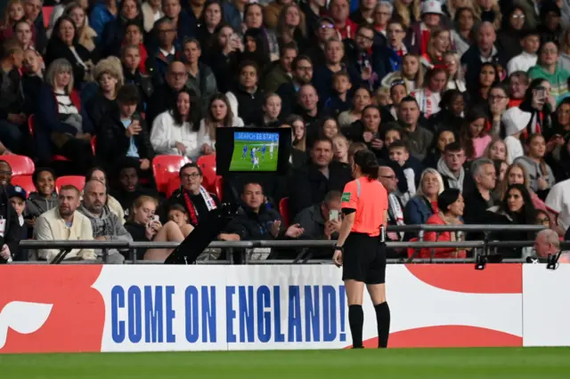 Referee Riem Hussein checks the VAR screen