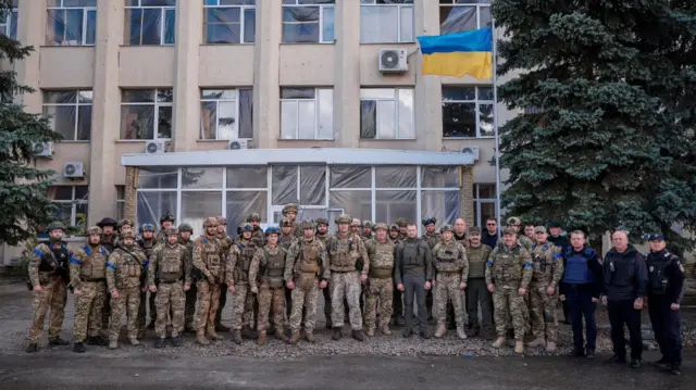 A large group of Ukrainian soldiers pose with their national flag